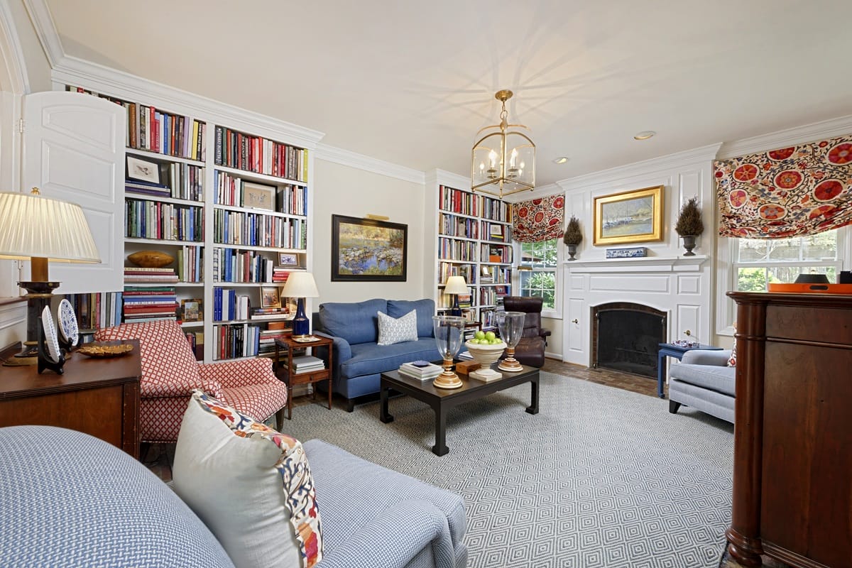 Cozy living room with built-in bookshelves, blue sofa, and patterned armchairs around a coffee table and fireplace.