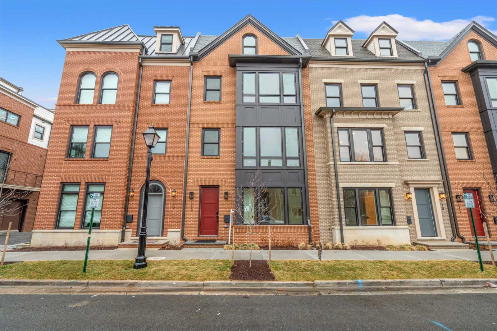 Row of brick townhouses with large front windows and a black street lamp along the sidewalk.
