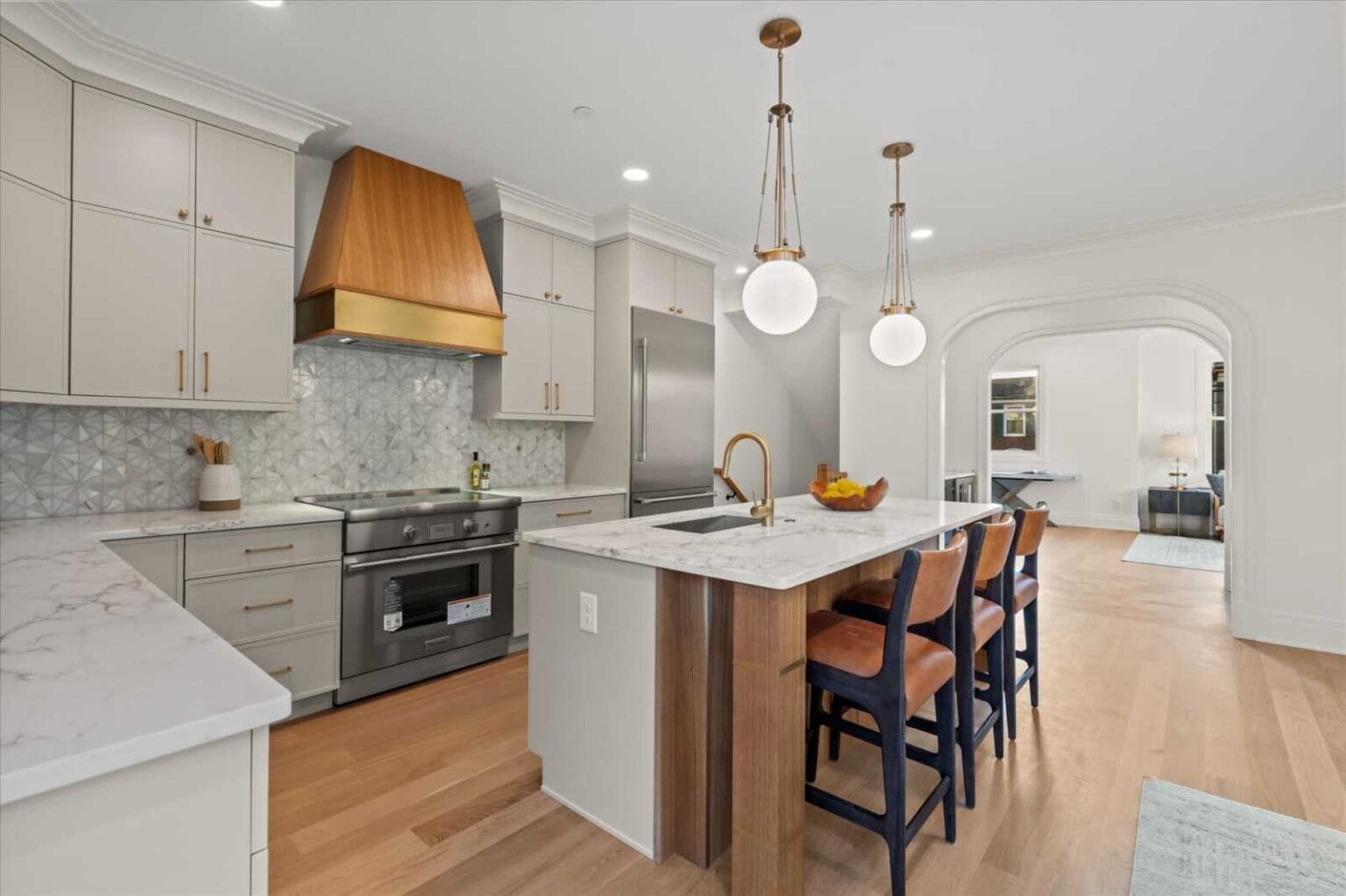 Modern kitchen with a marble island, copper range hood, and pendant lights over the bar seating area.