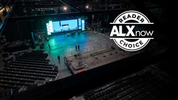 Wide shot of an arena stage being set up for ALX Now Reader Choice, with a large LED screen and empty seating areas nearby.