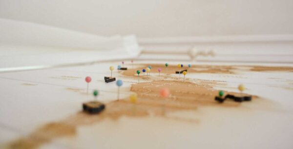 Tabletop map with multicolored pins marking locations, viewed from a low angle above the surface.