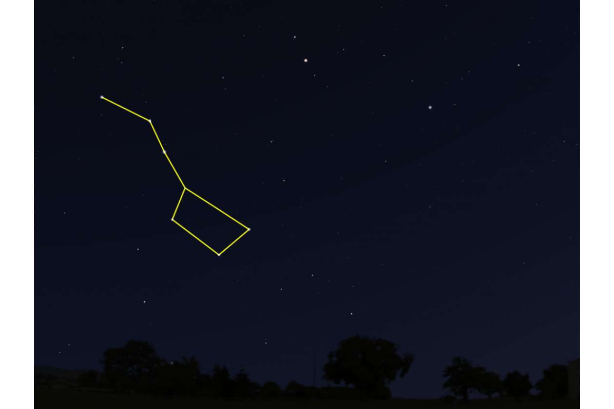 Night sky with a yellow outline tracing a constellation over a dark treeline horizon.