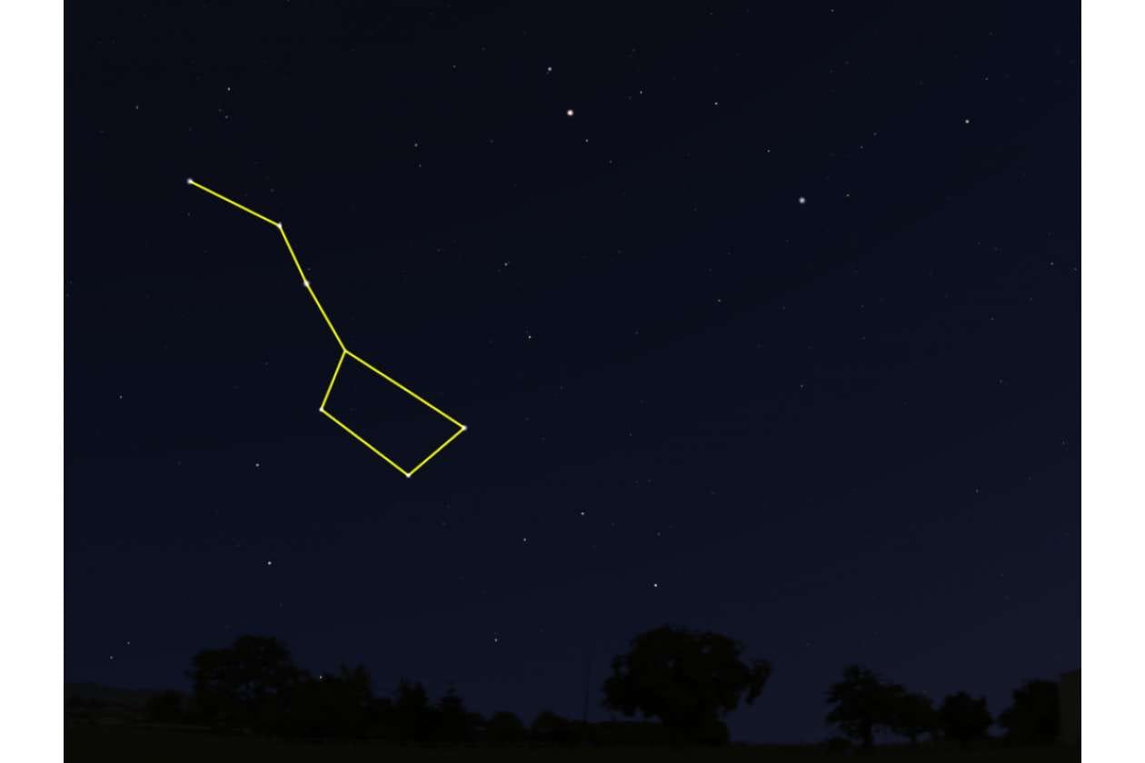 Night sky at night with a stylized yellow line constellation outline, over a dark landscape with trees.