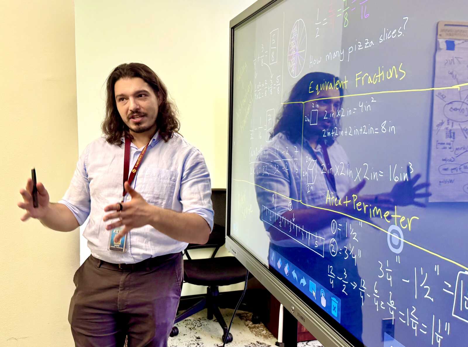 Instructor with long hair teaching math beside an interactive whiteboard filled with equations and fractions, gesturing with hands.