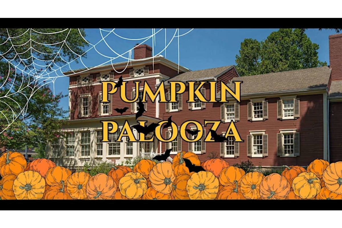 Promotional banner for a Halloween event: orange pumpkins lined along the bottom with a brick house in the background and 'PUMPKIN PALOOZA' in large yellow letters, plus bats and spider webs for a spooky theme.