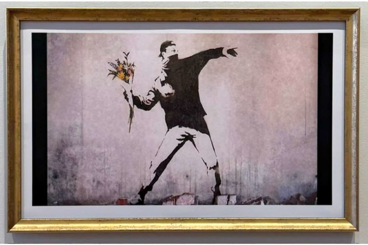 Stencil-style artwork of a man in a suit throwing a bouquet of flowers, framed and hung on a wall with a pinkish background.