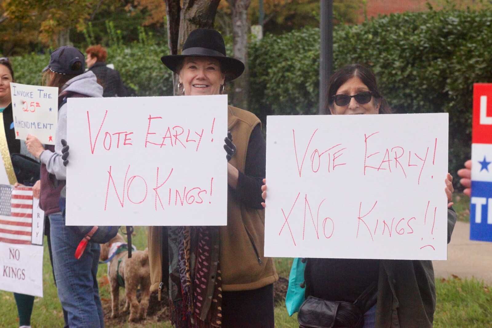 Group of protesters holding signs that read 'Vote Early! No Kings!' at a rally.