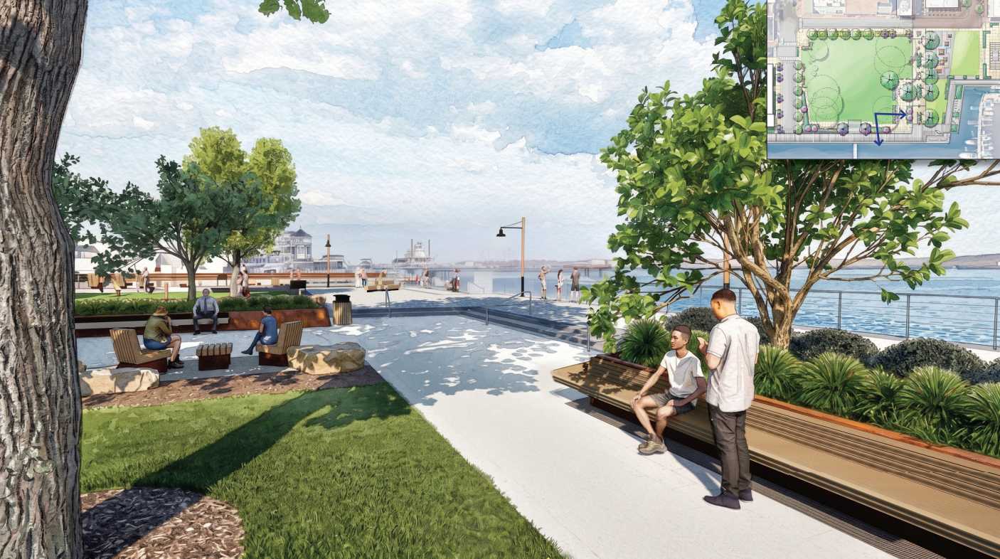 People sit on benches along a waterfront park with trees, grass, and a broad promenade extending toward the water.