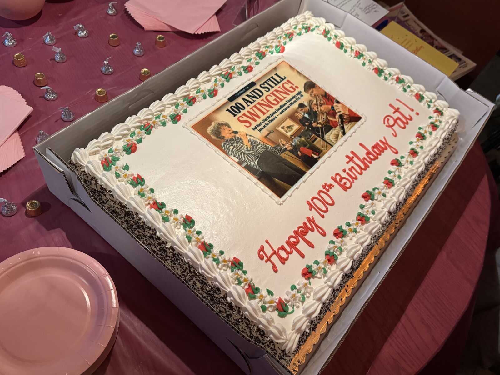 Rectangular birthday cake with white icing, red-green border, and a vintage photo panel saying '100 and still swinging!' on top.