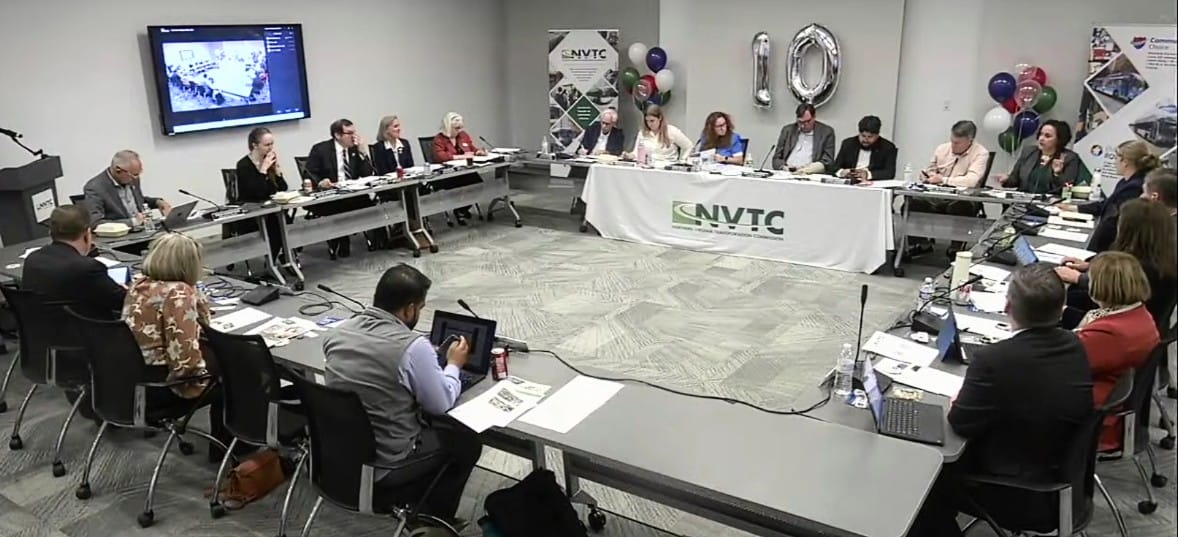 Oct. 1, 2026, Northern Virginia Transportation Commission meeting (screenshot via NVTC) | ALXnow Panel of professionals around a U-shaped conference table in a meeting room; an NVTC banner and balloons in the back, and a presentation screen on the wall.