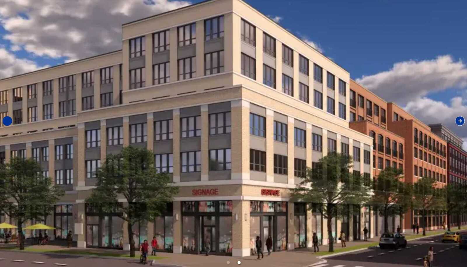 Corner of a multi-story mixed-use building with storefronts on the ground floor and people walking along a tree-lined city street.