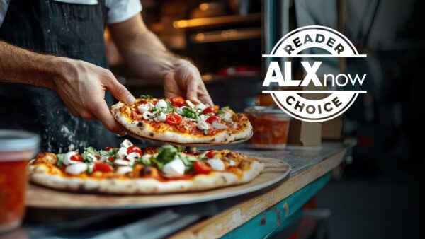 Pizza chef hands off a freshly topped pizza to be served, with two pizzas on a wooden counter and a circular 'Reader ALX now Choice' badge on the right.